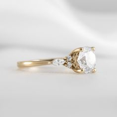 a gold ring with an oval cut diamond and two pear shaped diamonds on the side