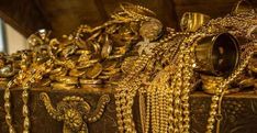 gold jewelry is on display in an antique box with chains and bells hanging from it