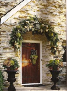 two large black planters sitting in front of a door with flowers on the side