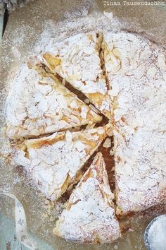 a cake with powdered sugar on top is sitting on a table next to a spoon