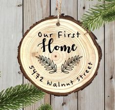 a personalized ornament hanging on a tree slice with the words, our first home