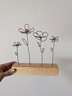 a hand holding a piece of wire with flowers on it