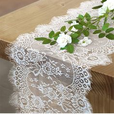 white flowers are sitting on top of a wooden table with lacy doily over it