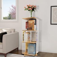 a book shelf with several books on it in front of a white couch and window