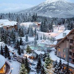 an aerial view of a resort in the mountains with snow on the ground and trees around it