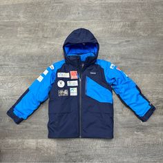 This Patagonia Snowshot Jacket Is Perfect For Young Boys Who Love Skiing. With Its Classic Fit And Mid-Length Design, It Is Both Stylish And Practical. The Jacket Features A Hooded Collar And A Zip Closure, Making It Easy To Put On And Take Off. Made With A Blended Fabric That Includes Nylon And Polyester, This Jacket Is Durable And Machine Washable. The Blue Color And Solid Pattern Give It A Sleek And Modern Look, While The Logo Accents Add A Touch Of Style. It Is Designed For Skiing In Fall, W Hooded Blue Skiing Outerwear, Blue Hooded Skiing Outerwear, Blue Long Sleeve Skiing Jacket, Blue Long Sleeve Outerwear For Skiing, Casual Blue Skiing Outerwear, Casual Blue Outerwear For Skiing, Blue Hooded Ski Season Outerwear, Blue Sporty Ski Season Outerwear, Blue Sporty Outerwear For Ski Season