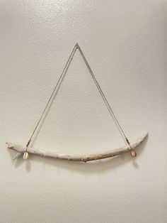 a piece of driftwood hanging on the wall with two strings attached to it,