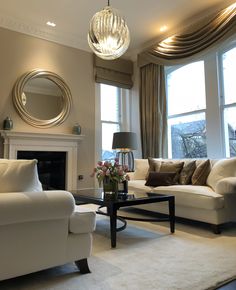 a living room filled with furniture and a fire place in front of two large windows