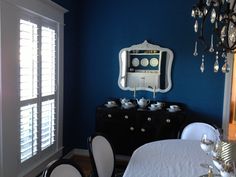 a dining room with blue walls and white table cloth on the table, chandelier hanging from the ceiling