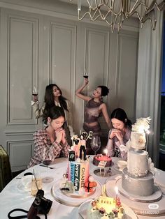 three women sitting at a table with cake and wine glasses in front of their faces