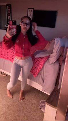 a woman taking a selfie in her bedroom while wearing leggings and a red shirt