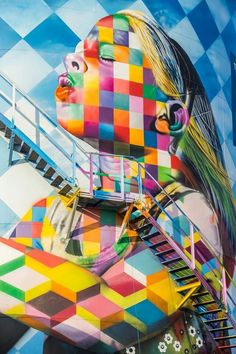 a woman's face painted on the side of a building with stairs leading up to it