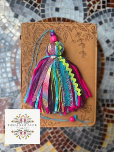 a book with a tassel on top of it next to a tile wall and colorful tiles