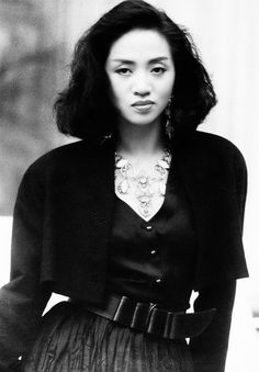 black and white photograph of a woman wearing a skirt, cardigan jacket and necklace