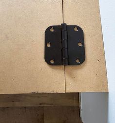 a black door hinge on top of a piece of cardboard