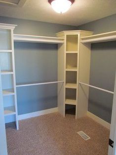 an empty walk in closet with white shelving and shelves on either side of the closet