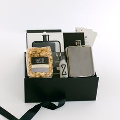 a gift box containing flasks, liquor and other personal care items with a black ribbon