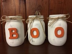 three mason jars with the word boo painted on them