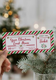 a person holding up a ticket for an event in front of a christmas tree with lights