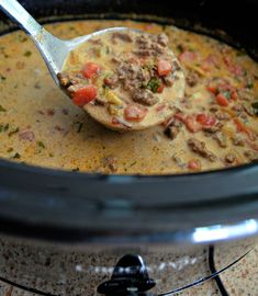 a spoon full of soup with meat and vegetables in it on top of an electric stove