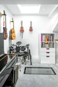 a room with several guitars and musical instruments on the wall, along with a piano