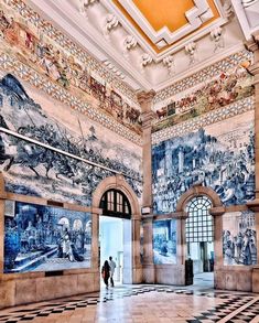 two people are standing in the middle of a room with large paintings on the walls