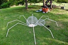 a large spider sculpture sitting on top of a lush green field next to a tree