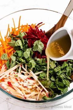 carrots, shredded parmesan cheese and greens in a glass bowl with dressing