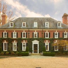 a large red brick house with ivy on the front and side walls, surrounded by hedges