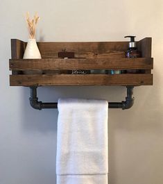 a towel rack made out of wooden planks and metal pipes with soap dispenser on top