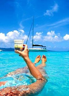 a person floating in the ocean holding up a cup