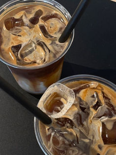 two iced coffees with ice and caramel are on the table next to each other