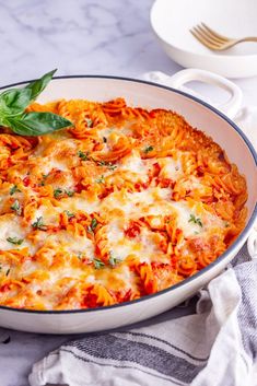 a casserole dish with tomato sauce and basil garnished with cheese on top