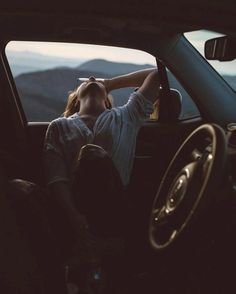 a woman sitting in the passenger seat of a car with her head resting on her hand