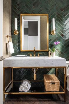 a bathroom with green tiled walls and gold fixtures, including a marble sink countertop