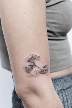 a woman's arm with a tattoo on it that has an image of a wave