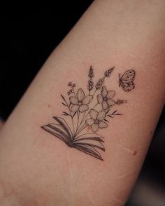 a tattoo on the arm of a woman with flowers and a butterfly flying over it