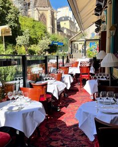 an outdoor dining area with tables, chairs and white tablecloths set for dinner