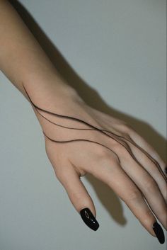 a woman's hand with black nail polish and wavy lines on the middle finger