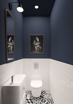 a white toilet sitting next to a sink in a bathroom under two pictures on the wall