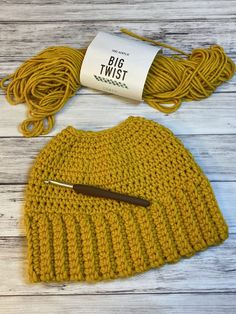 a yellow knitted hat next to a ball of yarn