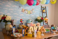 a table topped with lots of desserts and balloons