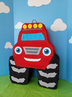 a red monster truck sitting on top of a green tablecloth covered floor next to a blue wall