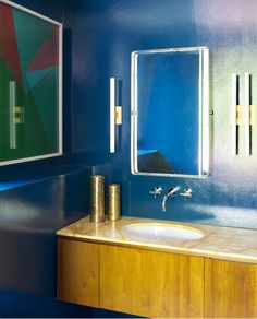 a bathroom with blue walls and wooden countertop, two mirrors on the wall above it