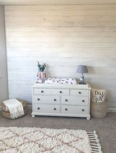 a white dresser sitting in the corner of a room next to a lamp and rug