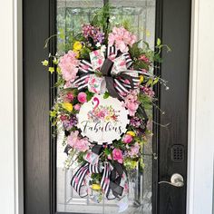 a front door decorated with a flamingo wreath and pink flowers on the front door