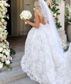 a woman in a wedding dress is walking down the stairs with flowers on either side