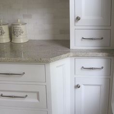 a kitchen with white cabinets and granite counter tops in the center, along with silver handles