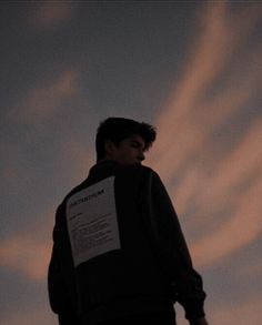 a man standing in front of the sky with his back to the camera and looking at something