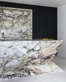 a marble counter top in the middle of a room with black cabinets and white walls